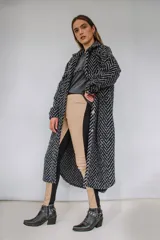 Tapado largo estilo chemise confeccionado en lana italiana tejida con patrón de espiga en color negro y gris. Presenta cierre frontal con botones y bolsillos con solapa.