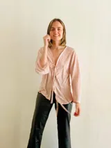 Blusa color rosa claro con textura plisada y escote en V con lazos para atar.