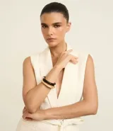 Kit de dos brazaletes rígidos, uno de color negro y otro de color dorado, con diseño minimalista y estructura articulada.