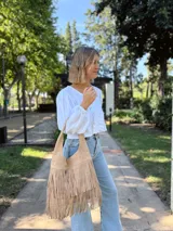 Cartera tipo hobo de cuero color beige con flecos en dos niveles.