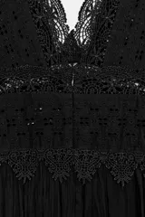 Vestido midi negro de escote pico y manga sisa, con detalles de bordados combinados a tono. Presenta un tejido plisado con efecto arrugado y cierre en la espalda con lazada y cremallera oculta.