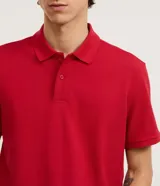 Remera polo de manga corta color verde militar, confeccionada en algodón peruano con cuello convencional y cierre de botones.
