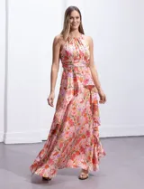 Vestido largo de gasa estampada con flores en tonos naranja, rosa y lila. Tiene escote halter, busto plisado, corte en la cintura con faja plisada y falda con sobrecapa y forro interno a tono.