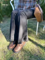 Botas cortas de cuero color marrón con suela track negra. Presentan dos correas ajustables con hebillas metálicas plateadas en el empeine y cierre lateral interno.