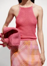 Top tejido de punto fino color rosado, con cuello halter, tirantes finos y espalda descubierta con cierre de lazo.