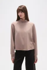 Buzo de manga larga color negro, con cuello alto tipo mock neck y corte holgado. Presenta costuras tipo raglán en los hombros.