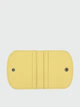 Tarjetero de cuero color amarillo, modelo Le Pliage Xtra de Longchamp, con diseño plegable y cierre de botón a presión.