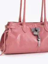 Cartera de hombro confeccionada en cuero vacuno color azul petróleo con acabado brillante. Presenta un diseño rectangular con herraje metálico tipo candado y dijes colgantes en el frente, además de correas laterales ajustables con tiras decorativas.