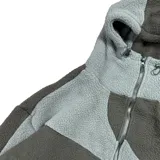 Campera con capucha confeccionada en tejido tipo polar, con diseño de bloques de color en tonos negro y gris oscuro. Presenta cierre frontal completo y ajuste regular.