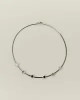 Collar de cadena tipo omega en color plateado, con dijes en forma de estrella de acrílico en tonos blanco y negro distribuidos a lo largo de la pieza.
