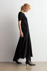 Vestido largo negro oversized con cuello redondo, mangas cortas y detalle fruncido en la cintura con cordón ajustable.