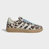 Championes Adidas Handball Spezial con diseño de estampado animal print tipo vaca en tonos marrón y blanco, con las icónicas tres tiras laterales en blanco, cordones celestes y suela de goma color caramelo.