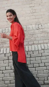 Camisa de lino blanca, de corte oversize, con mangas largas abullonadas, cuello mao y botones. Es más larga en la parte trasera e incluye un tajo en la espalda.