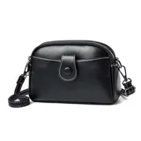 Cartera bandolera negra de cuero sintético con costuras blancas contrastantes, cierre superior con doble cremallera y bolsillo frontal con solapa y botón a presión. Incluye correa ajustable y desmontable.
