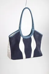 Bolso tipo tote de tela color crudo con detalles de cuero marrón en las asas y la base.