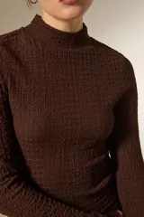 Polera de cuello alto y manga larga, confeccionada en tejido con textura arrugada y ajuste al cuerpo.