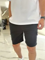 Bermuda deportiva tipo cargo de color negro, confeccionada en tejido de felpa, con bolsillos laterales con solapa y cintura elástica.