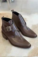 Botin de cuero color bordó con diseño de puntera fina y detalle de textura tipo reptil en el lateral. Cuenta con una tira ajustable con hebilla metálica y taco cuadrado.