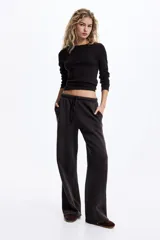 Pantalón tipo jogger de corte holgado y pierna ancha, confeccionado en felpa con interior suave. Presenta cintura elástica con cordón ajustable y bolsillos laterales discretos.