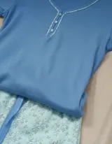 Pijama compuesto por una remera de manga corta azul con escote en V y un short celeste con estampado de motivos botánicos.