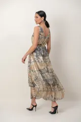 Vestido midi de fiesta color cobre con efecto metalizado y estampado abstracto en tonos grises y dorados. Cuenta con escote redondo, sin mangas, diseño cruzado en la espalda y un cinturón metálico dorado incorporado en la cintura. La falda tiene corte fluido y asimétrico, más largo en la parte trasera.