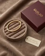 Esclava rígida de acero con baño de oro, con diseño grabado de guarda griega en toda su superficie.