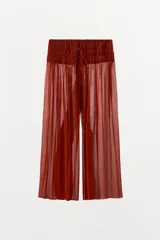 Pantalón semitransparente de pernera ancha, tiro medio y cintura elástica ajustable con lazadas, confeccionado en 100% viscosa.