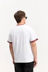 Remera marrón de manga corta confeccionada en algodón, con cuello redondo y ribetes en contraste de color tostado en el cuello y los puños. Presenta estampa frontal con la frase "your vibe attracts your tribe" y el logo de Mistral.
