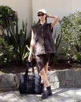 Chaleco de denim color gris oscuro con efecto lavado, corte oversize, cuello camisero, cierre frontal con botones metálicos y dos bolsillos frontales con solapa.