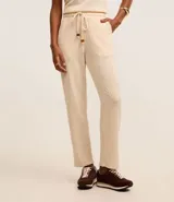 Pantalón zanahoria color crema, con cintura elástica, lazo, bolsillos laterales y superficie texturizada.