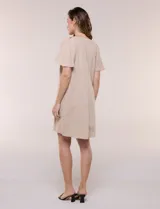 Vestido corto de silueta holgada y estilo túnica de la marca Signature, color beige, con escote en V, pliegues centrales en el frente y mangas cortas acampanadas.