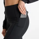 Calza deportiva negra de tiro alto, con bolsillos laterales y logo reflectivo en la pierna izquierda.