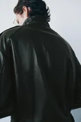 Chaqueta bomber de piel color verde oscuro, con cuello alto, manga larga con puño, bolsillos delanteros y trabillas en los hombros. Cierre frontal con cremallera y botones ocultos por solapa.