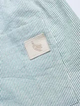 Shorts celestes con finas rayas verticales blancas, cintura elastizada con cordón ajustable y logo de la marca en la parte inferior.