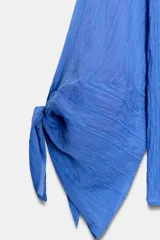 Camisa de cuello solapa y manga larga con detalle de lazos en los puños. Presenta un diseño de rayas verticales a tono y cierre frontal con botones ocultos.