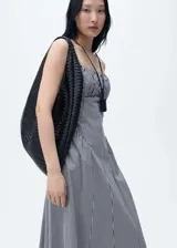 Vestido midi de corte evasé con estampado de cuadros vichy en blanco y negro. Presenta un diseño sin mangas con tirantes finos ajustables, escote recto con detalle fruncido y cierre de cremallera lateral.