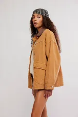 Campera oversize de denim en color marrón, con hombro caído, cuello de lona marrón en contraste, bolsillos frontales con solapa, cierre de botones metálicos y puños abotonados.