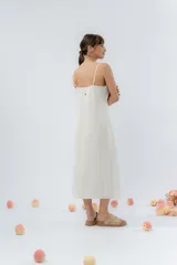Vestido midi celeste de tejido tipo seda fría, con breteles finos regulables, botones de madera decorativos en el frente, pliegues decorativos en la cintura y cierre invisible en el costado.