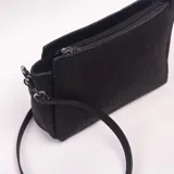 Bandolera negra con textura efecto cocodrilo, diseño estructurado y correa ajustable para el hombro.