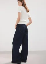 Pantalón de jean de corte recto y tiro medio, confeccionado en denim de color azul oscuro con costuras en contraste.