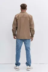 Camisa de pana color tostado, con cuello clásico, cierre frontal de botones y bolsillo en el pecho con etiqueta pequeña.