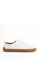 Zapatillas de cuero blanco con diseño minimalista, cordones al tono y suela de goma color suela con costura vista.