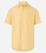 Camisa de manga corta confeccionada en mezcla de lino y algodón, con cuello inglés, cierre frontal de botones y bolsillo en el pecho. Presenta un corte comfort holgado y diseño liso.