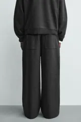 Pantalón de corte wide fit en tejido con acabado cepillado, color gris oscuro. Presenta cintura elástica con cordón ajustable, bolsillos delanteros y bolsillos traseros de plastrón.