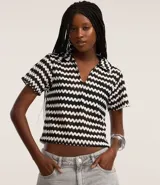 Blusa femenina de punto con cuello polo, mangas cortas y estampado de rayas horizontales en tonos naranja, marrón, blanco y verde.