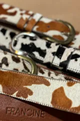Cinto de cuero vacuno con pelo natural, con diseño de manchas tipo animal print. Cuenta con hebilla metálica y costuras reforzadas.