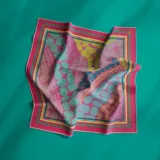 Pañuelo cuadrado de seda color fucsia con estampado de círculos de colores y borde con diseño geométrico.