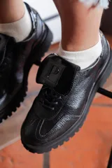 Zapato Oxford negro de cuero con cordones, suela track y detalle de aplique con logo en la lengüeta.