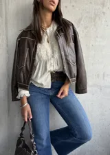 Camisa beige de manga larga con cuello mao y escote en V. Presenta detalles bordados en el canesú y los hombros, y volados en los puños.