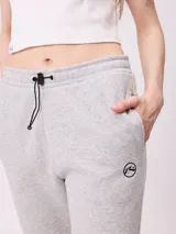 Pantalón tipo babucha de algodón y poliéster, con cintura elástica ajustable mediante cordón, bolsillos laterales y puños elásticos en los tobillos. Presenta un pequeño logo bordado en la pierna izquierda.